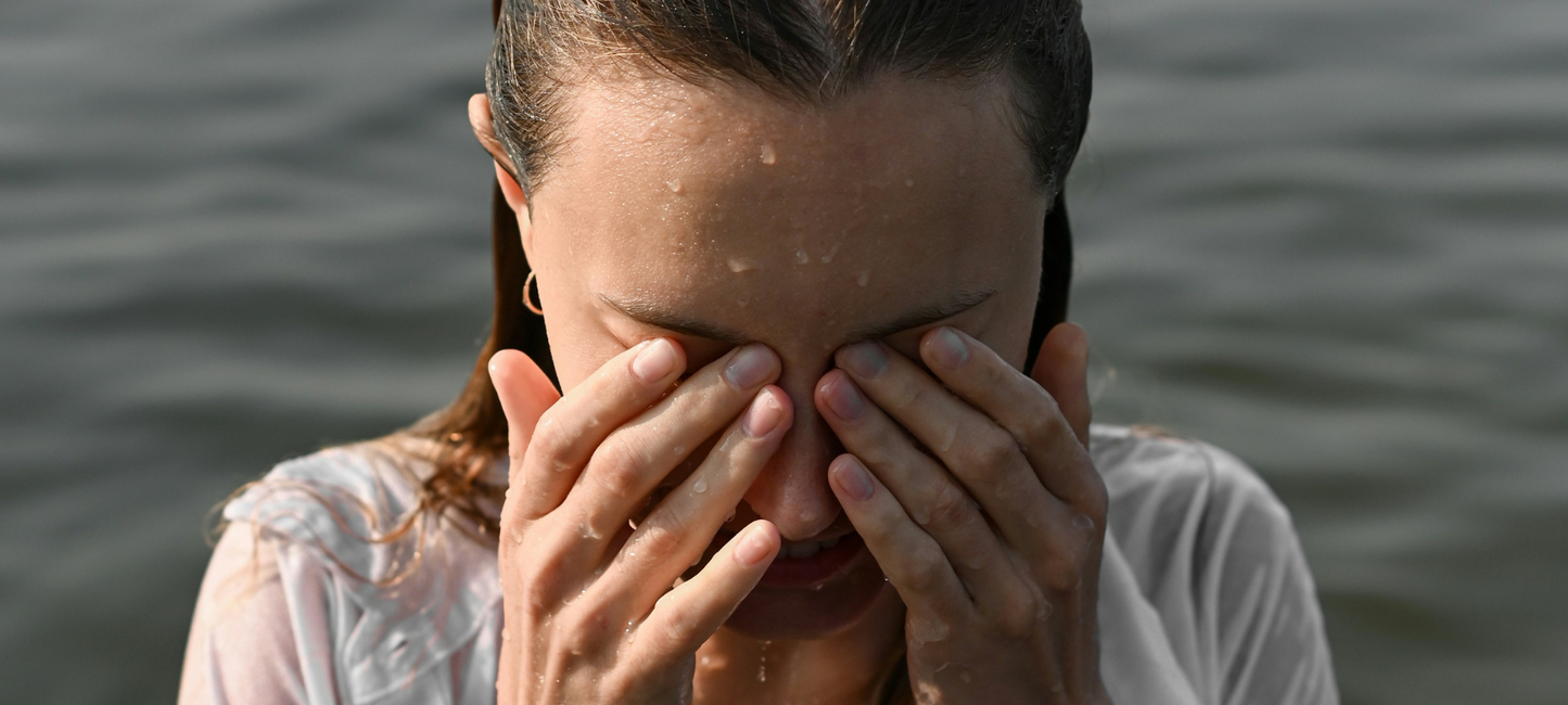 Woman gently wiping her face, demonstrating proper skincare routine for hydrated and glowing skin.