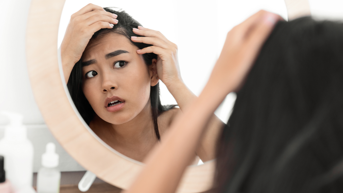 Woman examining thinning hair at the part while considering a scalp care routine
