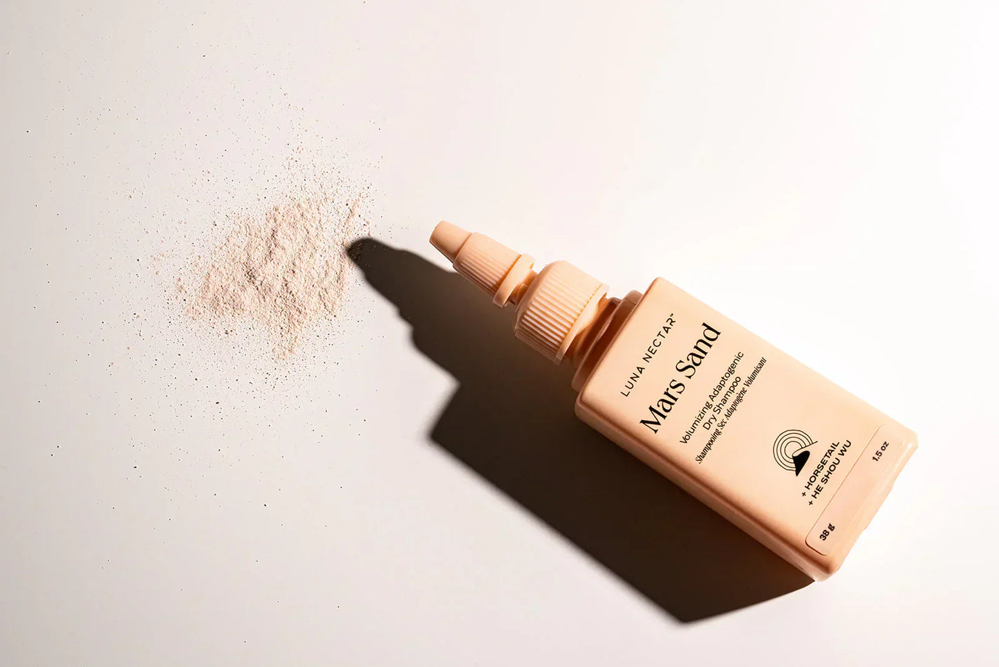 Benzene-free dry shampoo powder spilling from Luna Nectar Mars Sand bottle