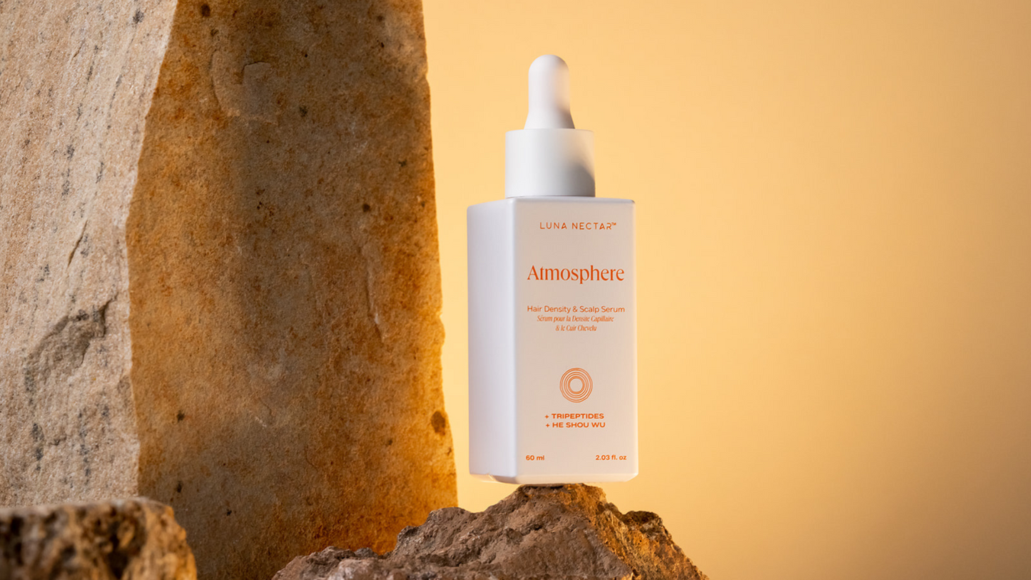 Atmosphere Multi-Peptide Hair Density & Scalp Serum bottle on stone, natural lifestyle setting.