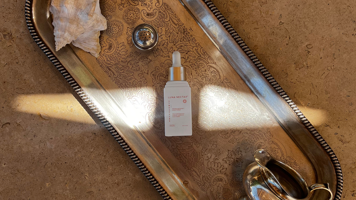 Luna Nectar Atmosphere Multi-Peptide Hair Density & Scalp Serum bottle on an antique silver tray, symbolizing luxury, clean chemistry, and investment in hair wellness.