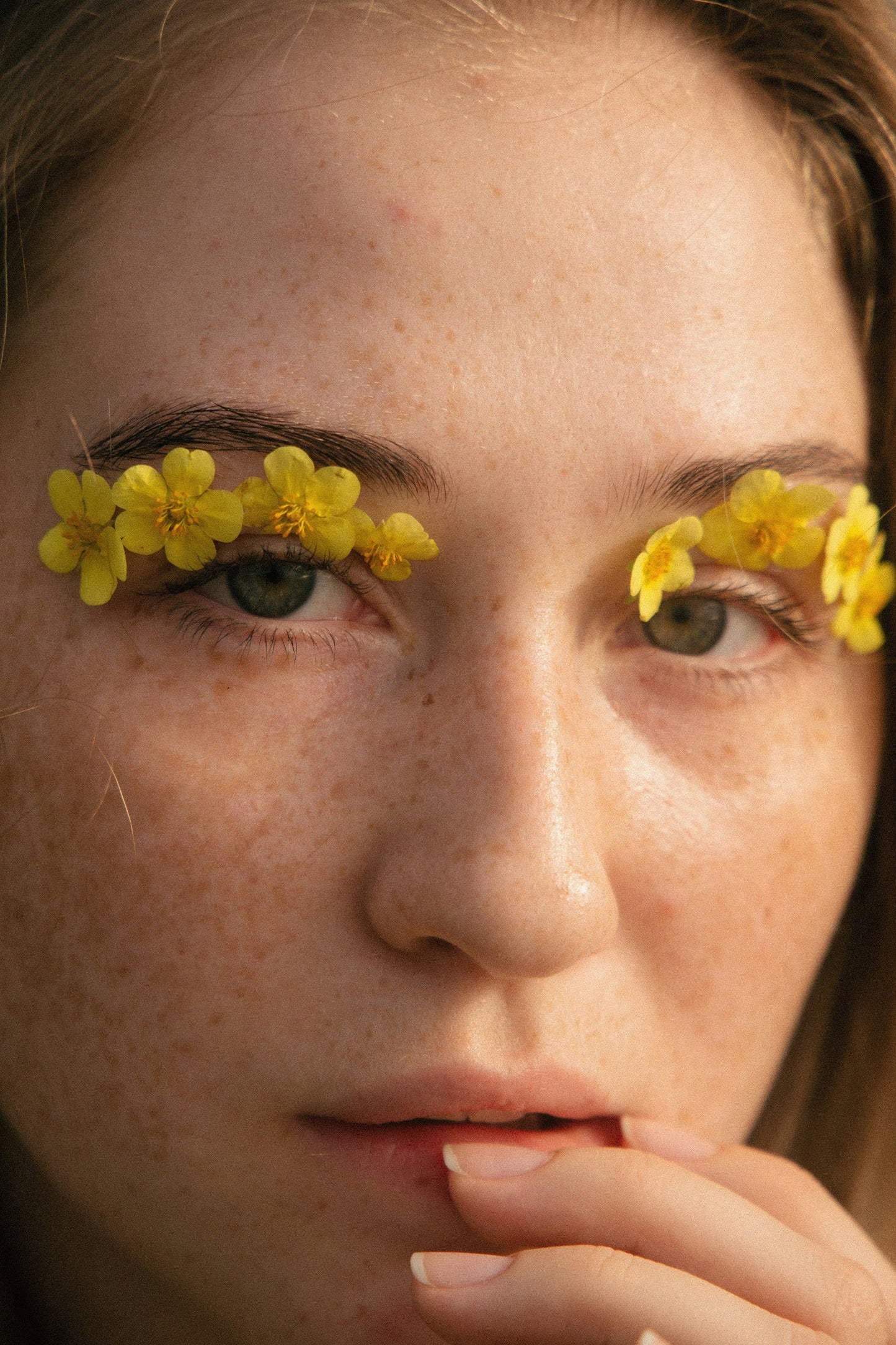 Woman with flowers over her eyes symbolizing natural, gentle lash care and clean beauty rituals